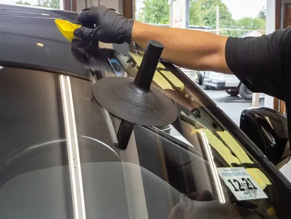 A man is working on a car windshield
