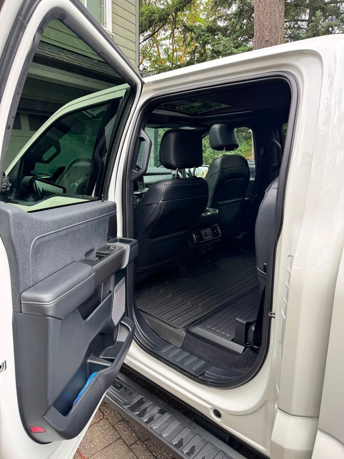 Open truck door showing gray interior, running board, and empty rear seat area.