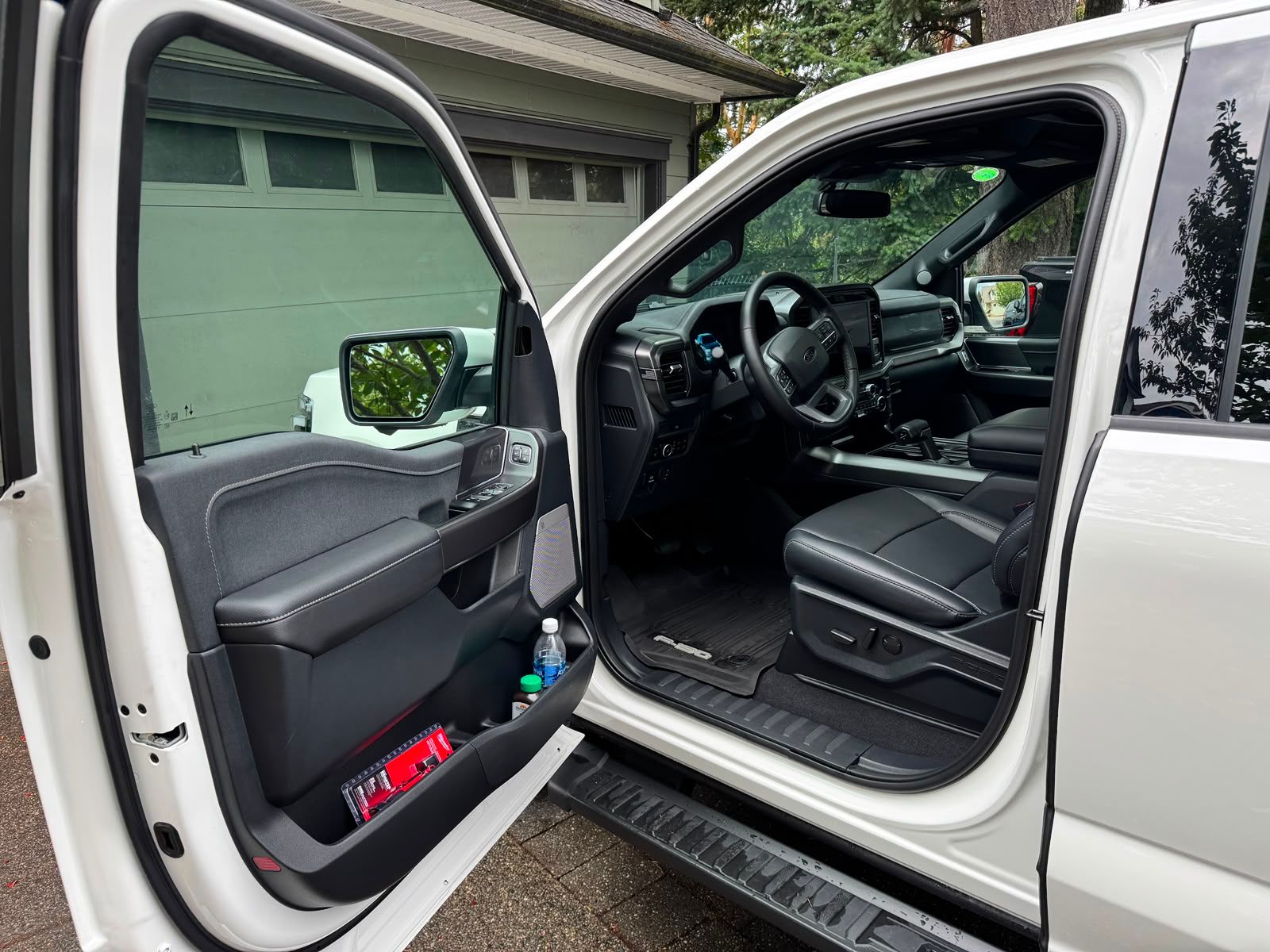 Open truck door showing black leather interior and running board in driveway