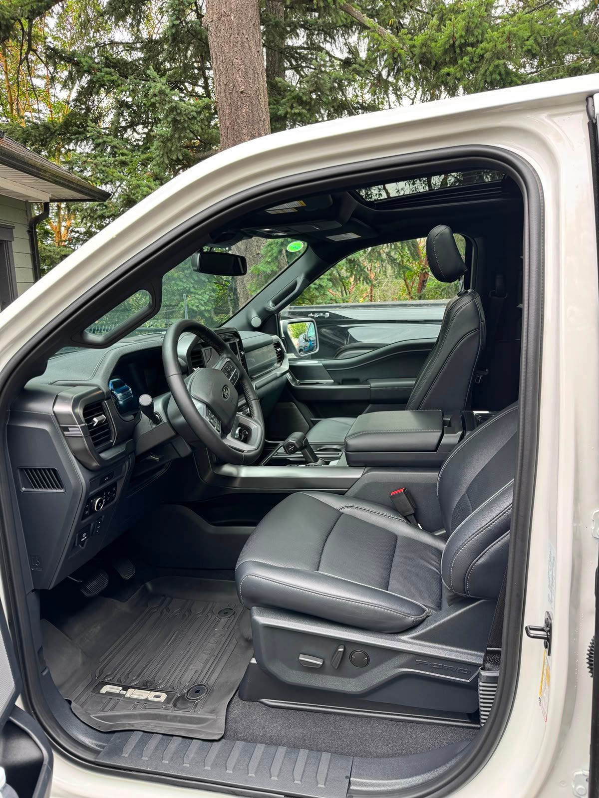 Open driver's side door showing black leather car interior and steering wheel.