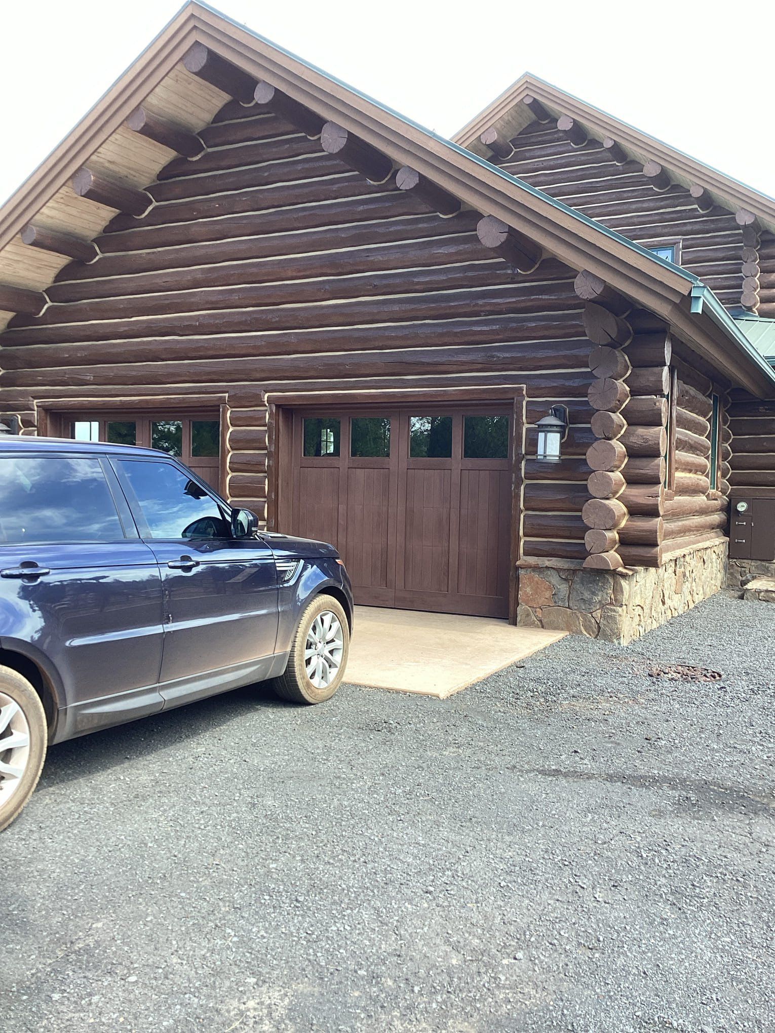 A car is parked in front of a log cabin.