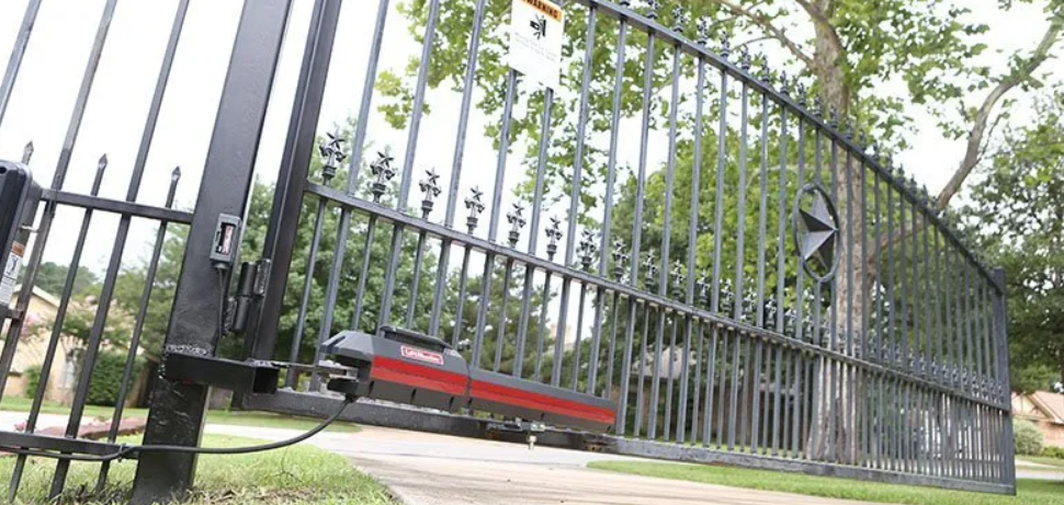 A wrought iron gate with a motor attached to it is open.