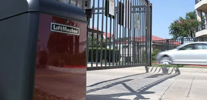 A red liftmaster garage door opener is sitting next to a gate.