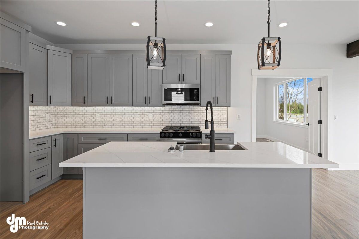 Modern gray kitchen with white island, pendant lights, and a large windowed door