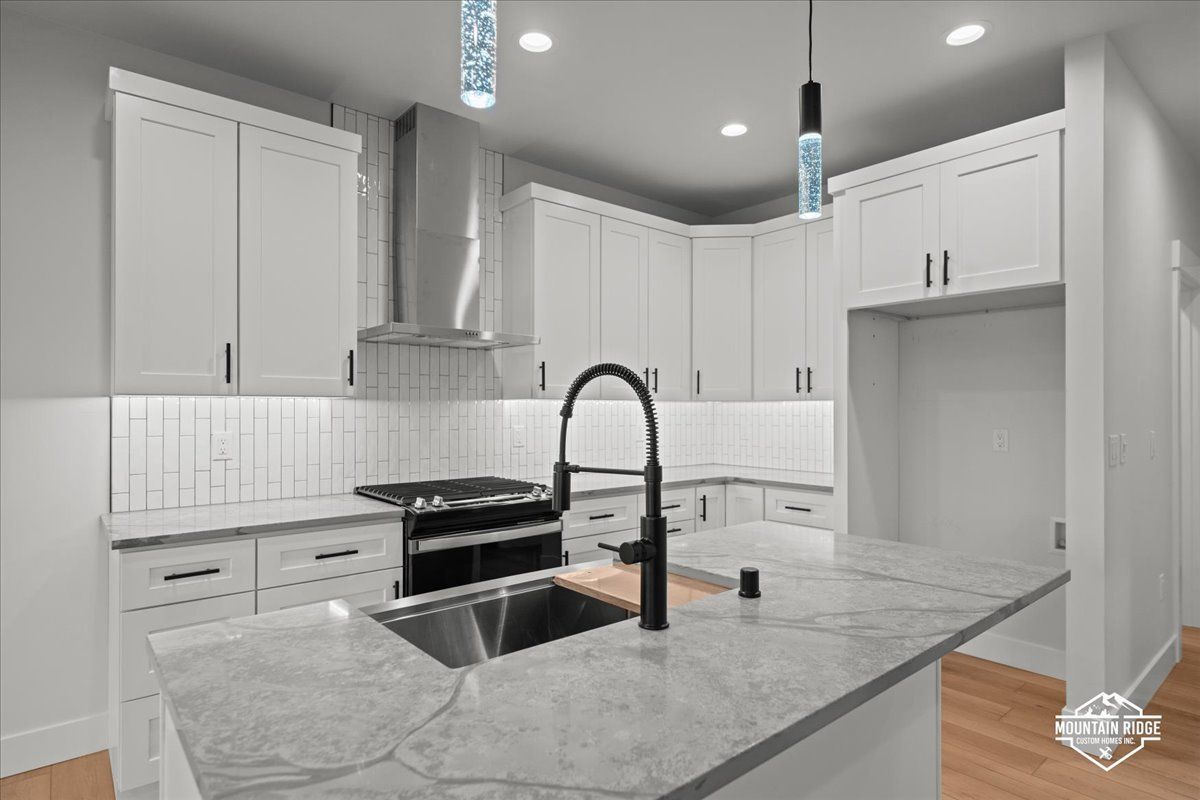 Modern white kitchen with gray marble island, black faucet, and stainless steel appliances