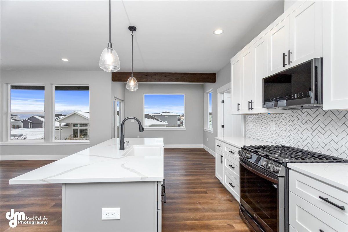 Bright modern kitchen with white cabinets, island, stainless appliances, and hardwood floors