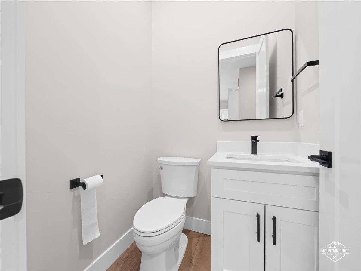 Small white bathroom with toilet, vanity sink, mirror, and towel rack