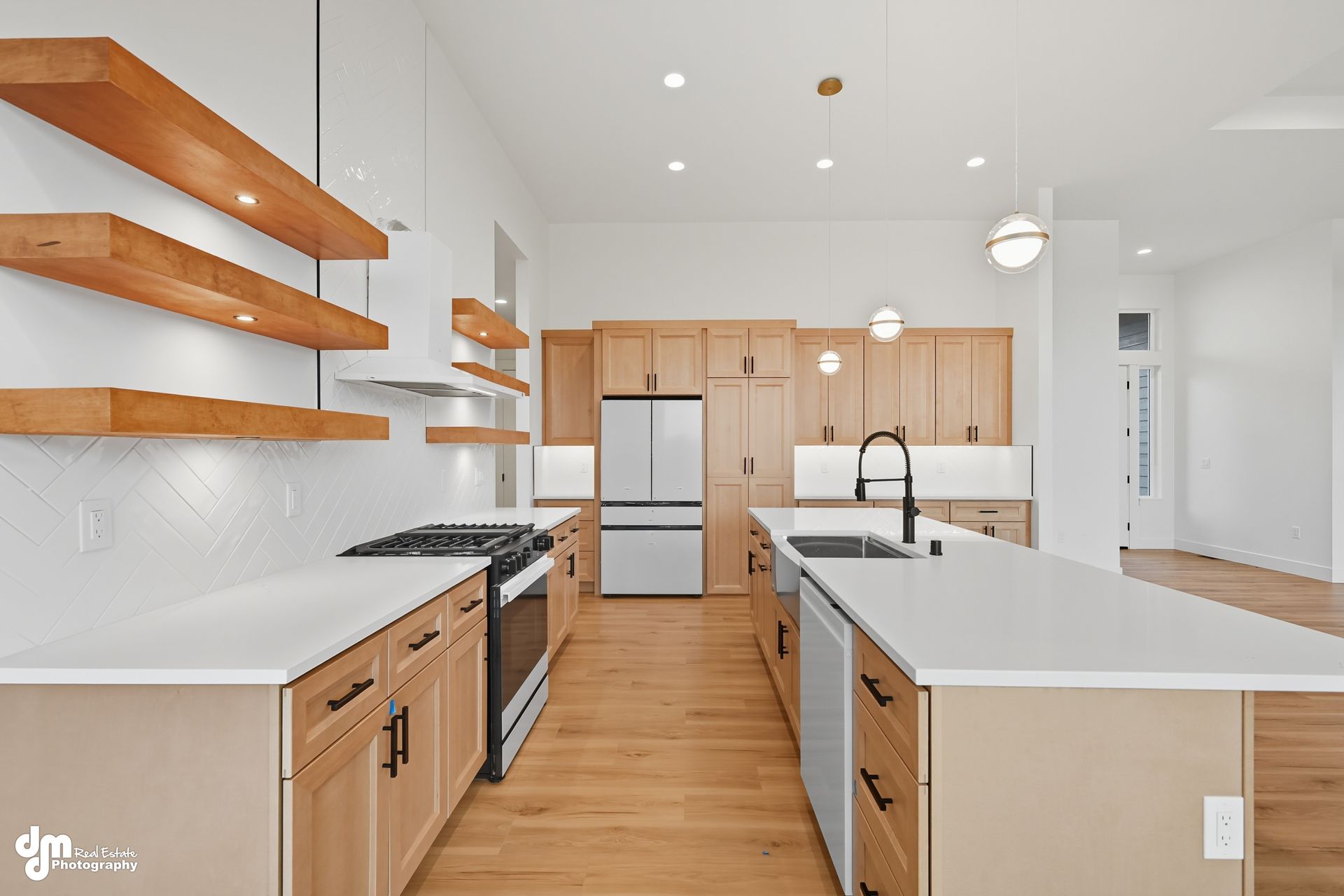 Bright modern kitchen with white counters, wood cabinets, floating shelves, and stainless appliances