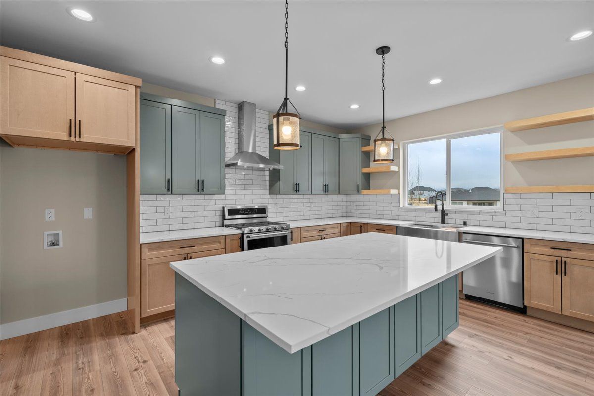 Modern kitchen with blue cabinets, white island, wood floors, and large windows