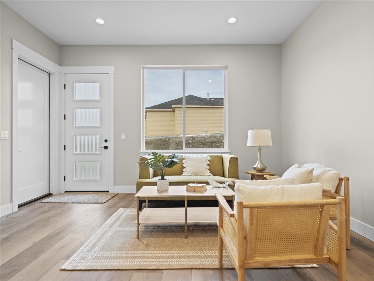 Bright living room with wicker chairs, light rug, coffee table, and a window facing another building