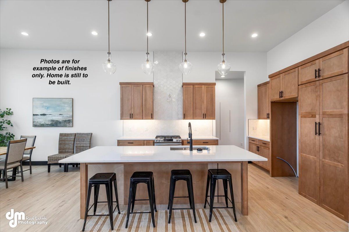 Modern kitchen with white island, black stools, wood cabinets, and pendant lights in an open dining area