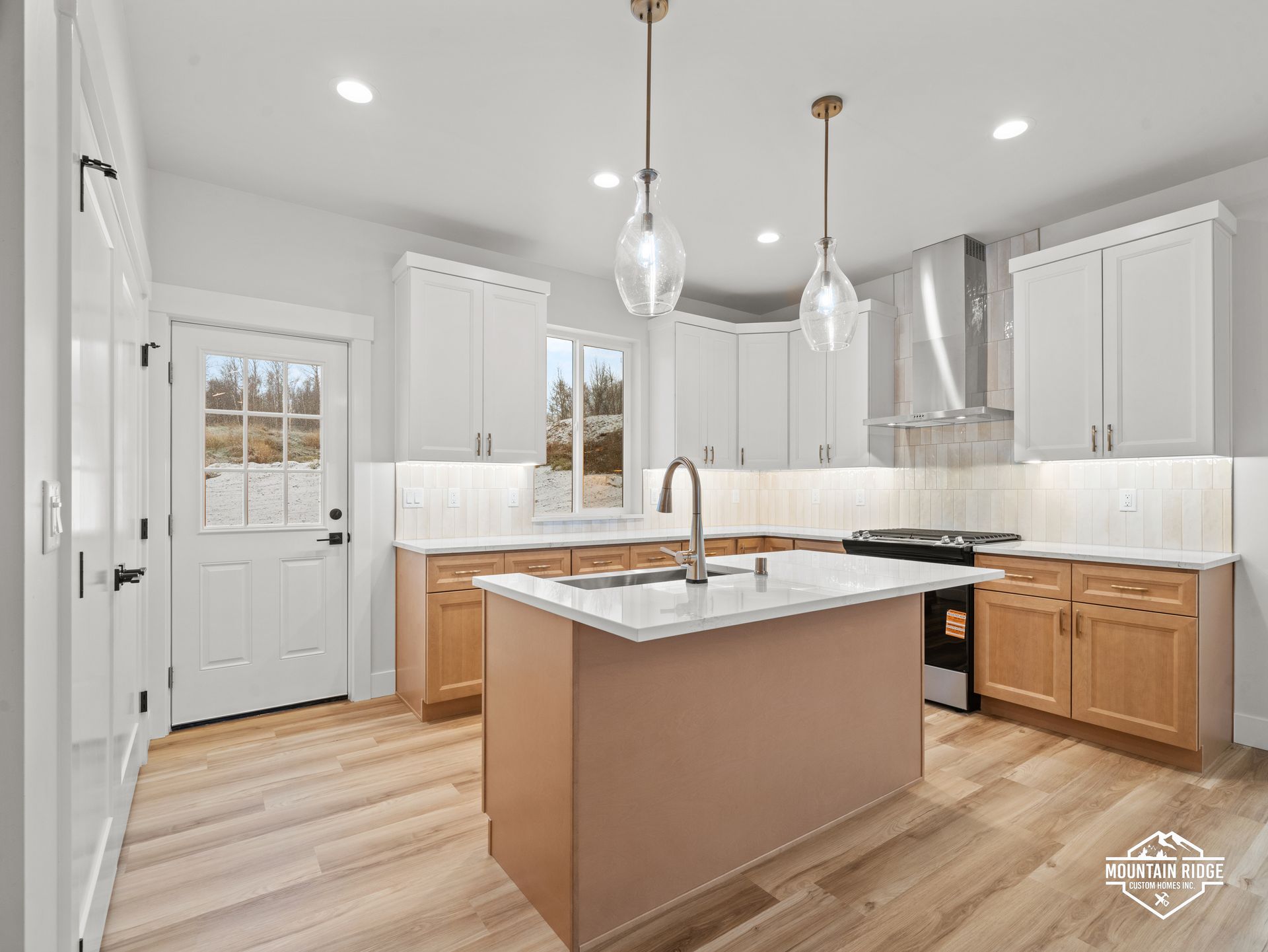 Bright modern kitchen with white cabinets, wood floors, stainless appliances, and a central island