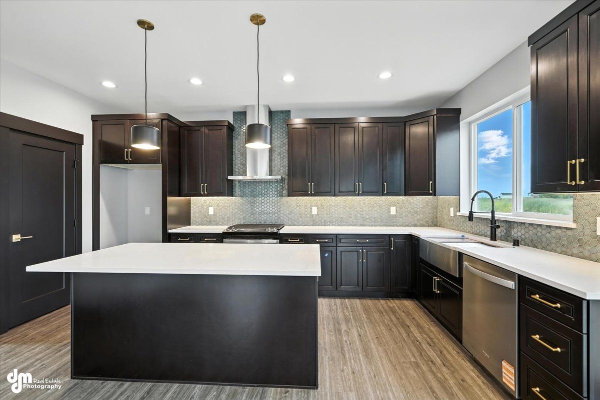 Modern kitchen with dark cabinets, white island, stainless appliances, and wood-look floors