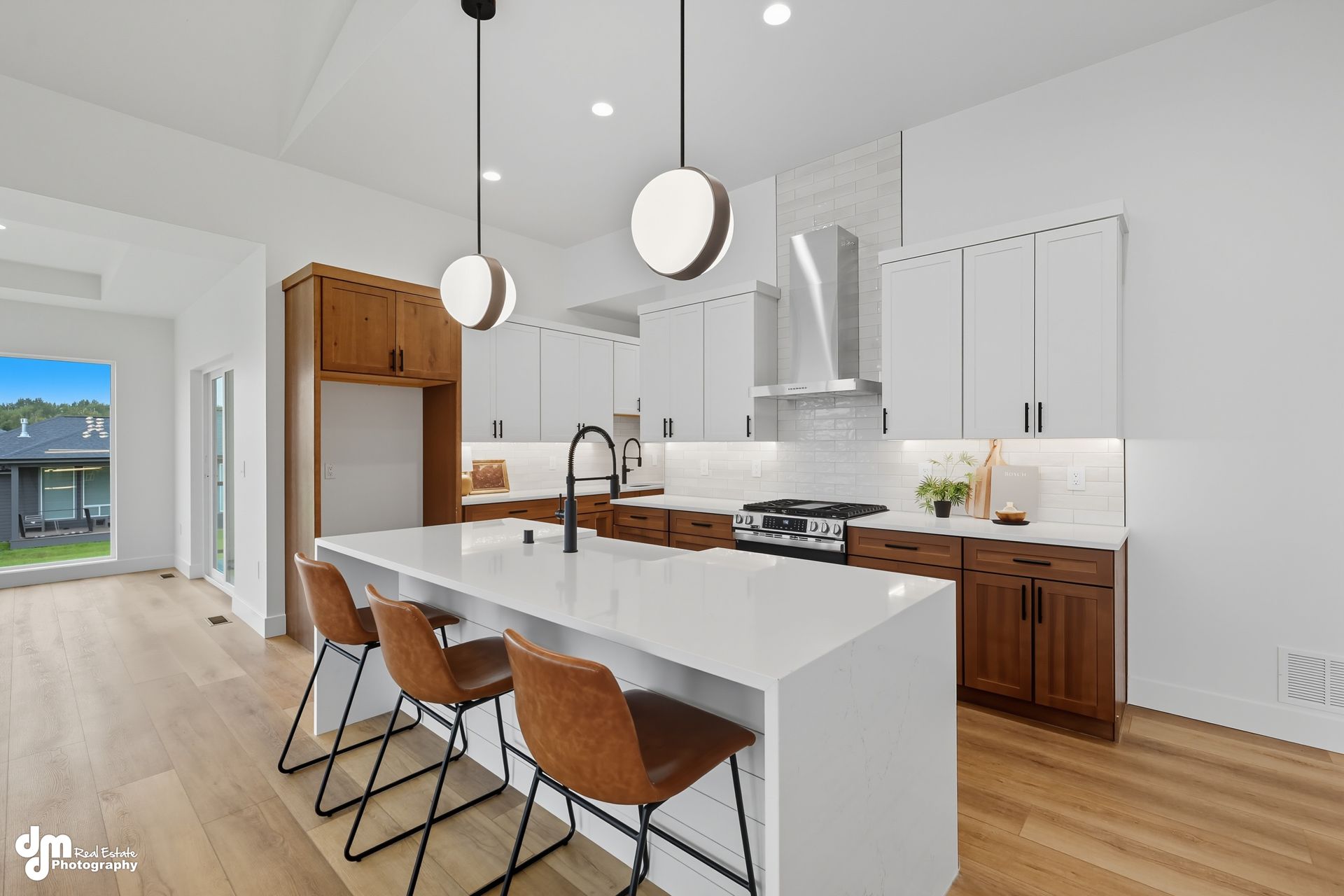 Modern kitchen with white island, wood cabinets, pendant lights, and two stools
