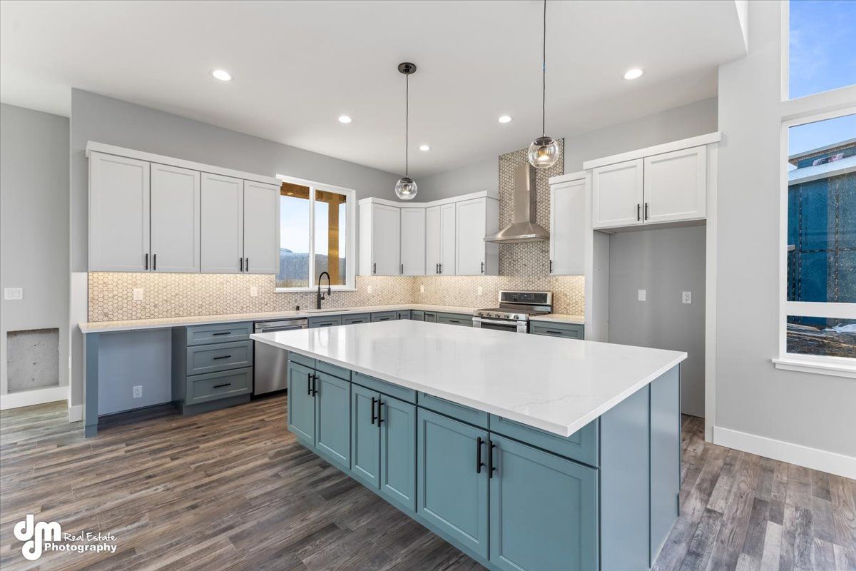 Bright modern kitchen with gray cabinets, blue island, white countertops, and wood-look floors