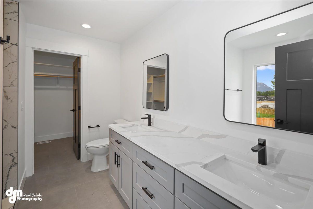 Modern bathroom with double vanity, large mirrors, walk-in closet, and open exterior door to a balcony.