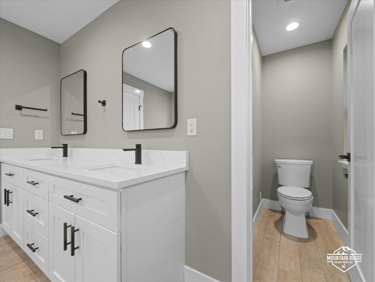 Bright bathroom with white vanity, mirror, and toilet in a narrow alcove.