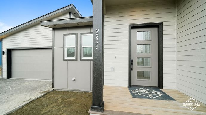 Modern house exterior with garage, white siding, and a covered front entry with a black column