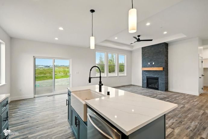 Bright open kitchen with island, pendant lights, fireplace, and sliding doors to patio
