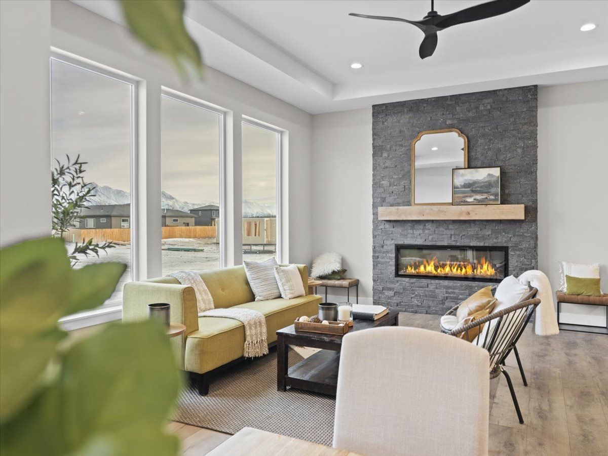 Bright living room with gray fireplace, yellow accents, large windows, and a ceiling fan