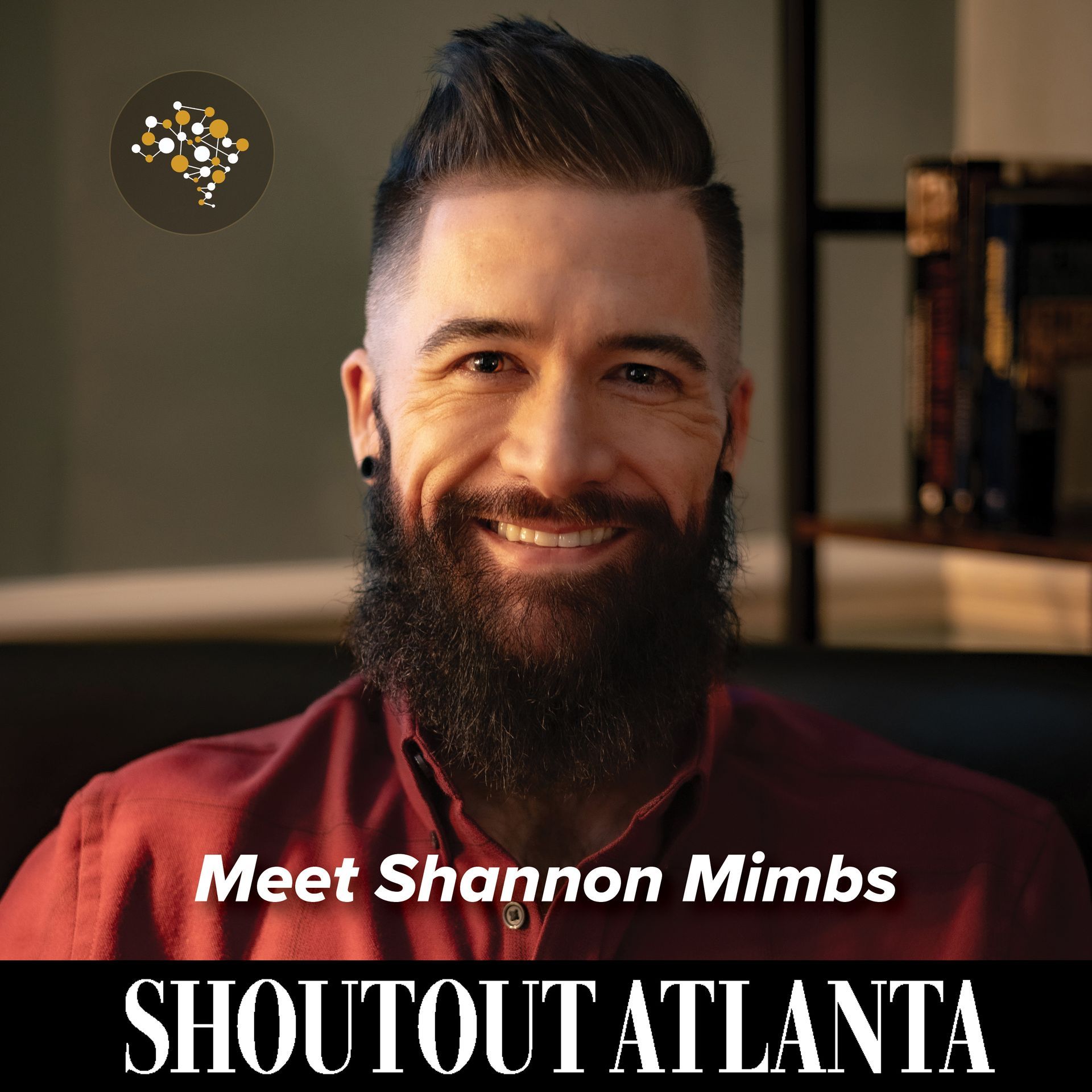 A man with a beard is smiling and wearing a red shirt.