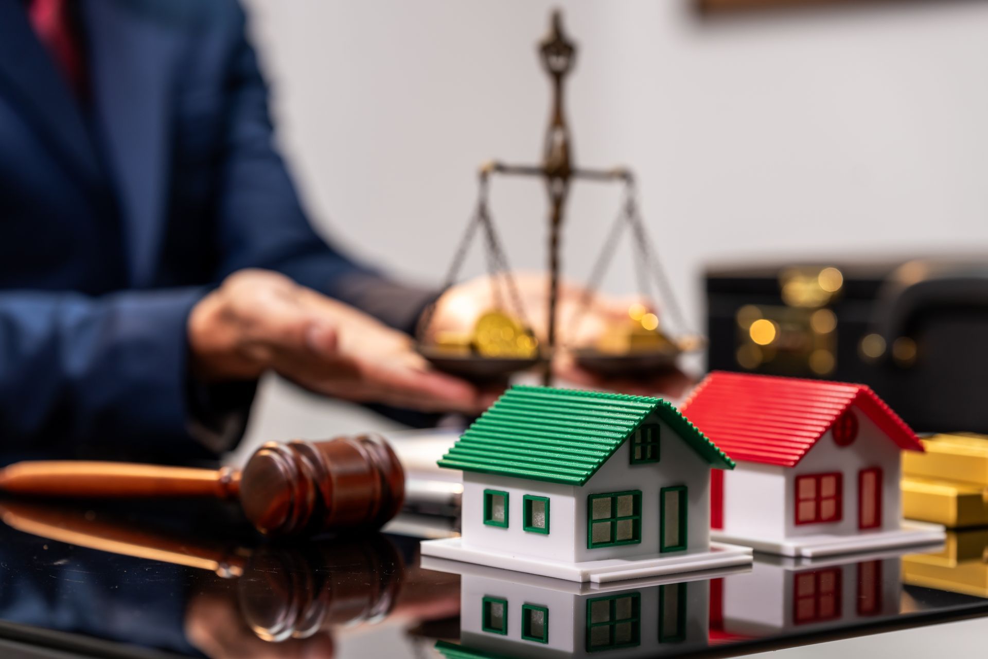 real estate attorney behind a desk with a wooden gavel, brass justice scales and two model houses. real estate attorney behind a desk with a wooden gavel, brass justice scales and two model houses.