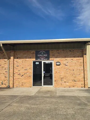 Brick building entrance with glass double doors and a sign above, under a blue sky.
