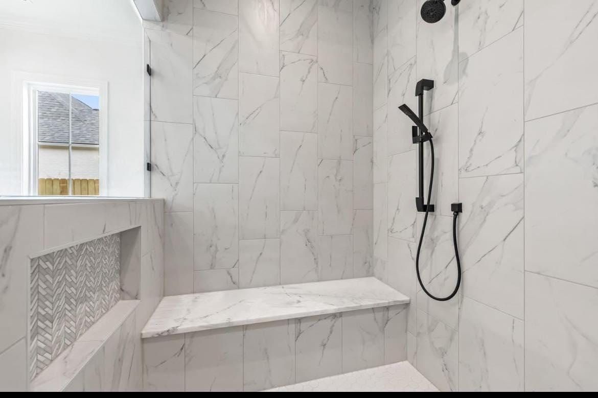 Modern white-tiled walk-in shower with bench and black shower fixture