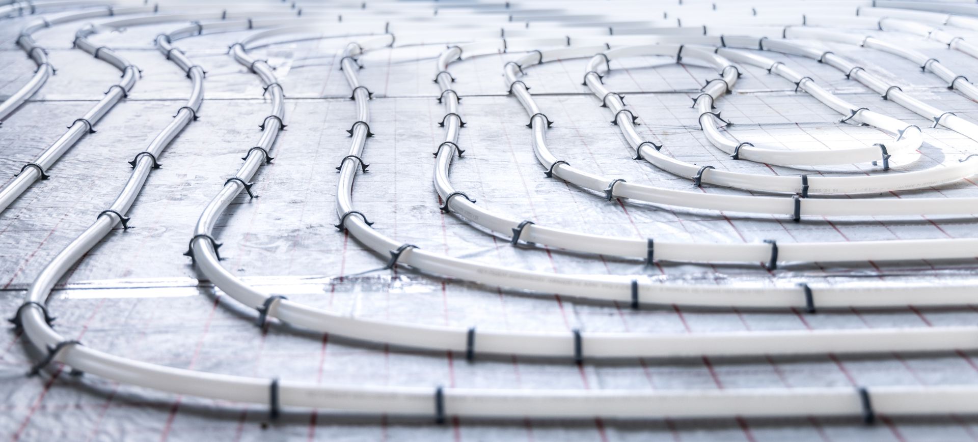 Curved white cable conduits laid in parallel rows on a light surface