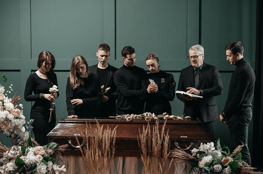family grieving at funeral standing over casket