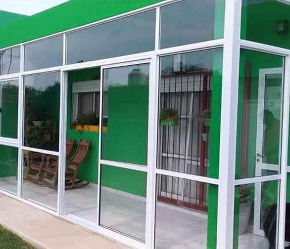 Trabajador midiendo un marco de ventana blanco dentro de una habitación parcialmente renovada.