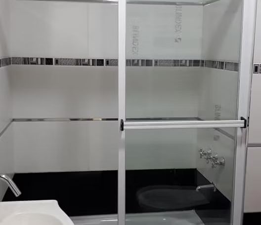 Trabajador midiendo un marco de ventana blanco dentro de una habitación parcialmente renovada.