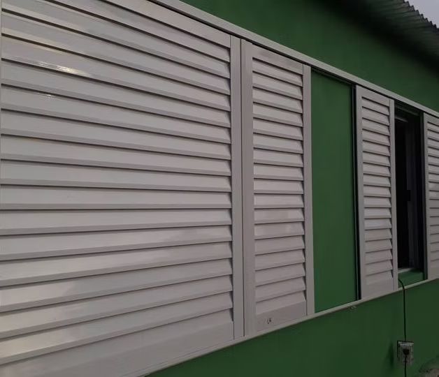 Trabajador midiendo un marco de ventana blanco dentro de una habitación parcialmente renovada.