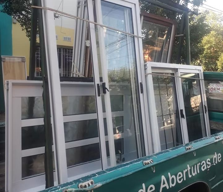 Edificio de piedra con grandes ventanales, una puerta blanca y césped irregular en la fachada.