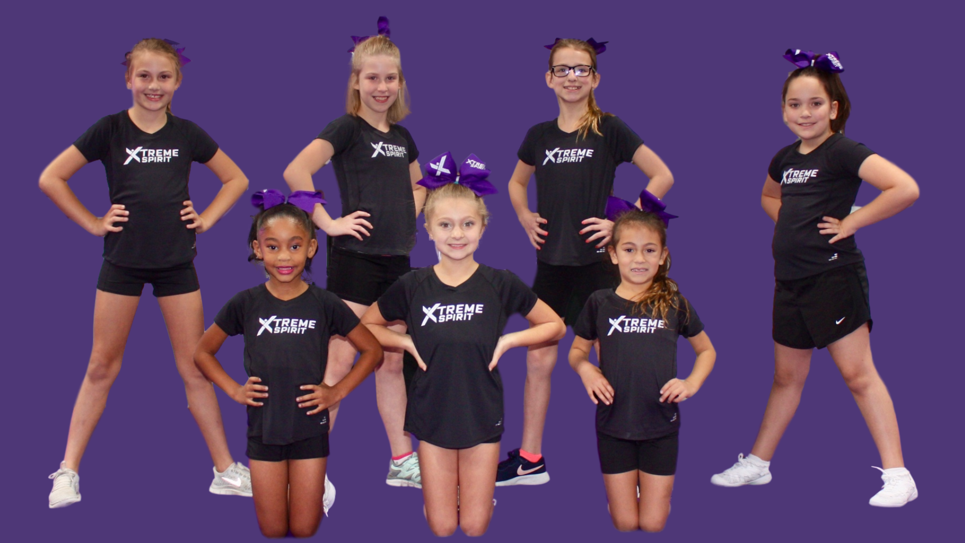 Two young girls are cheering with pom poms in a gym.
