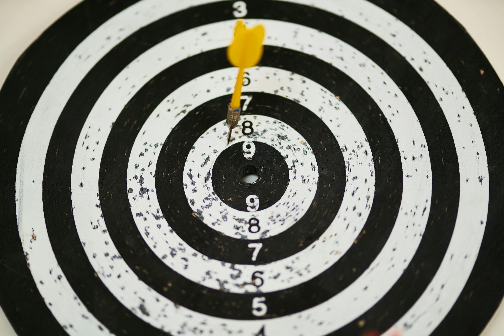 Yellow dart in center of black and white dartboard.