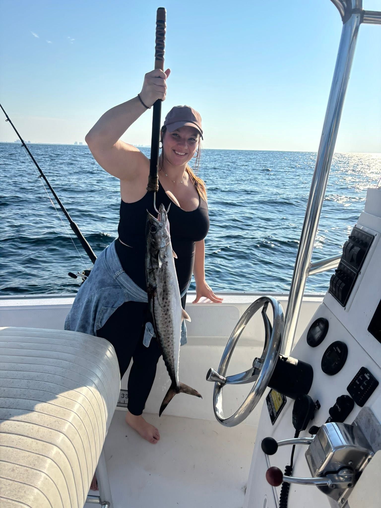 Person holding up a fish on a boat in sunny open water