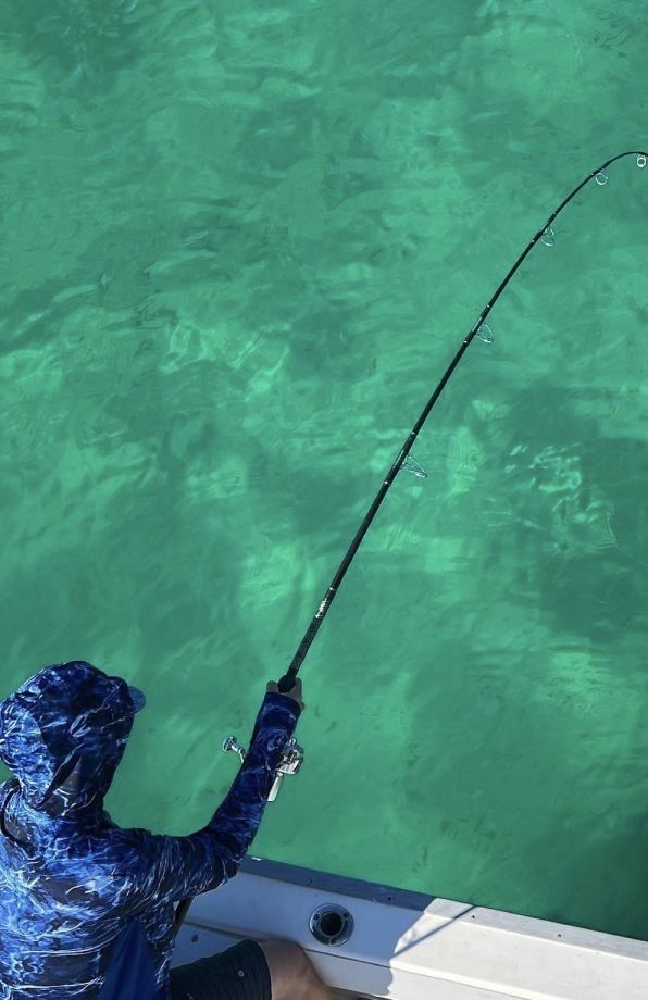 Person in blue camo jacket fishing from a boat over green water