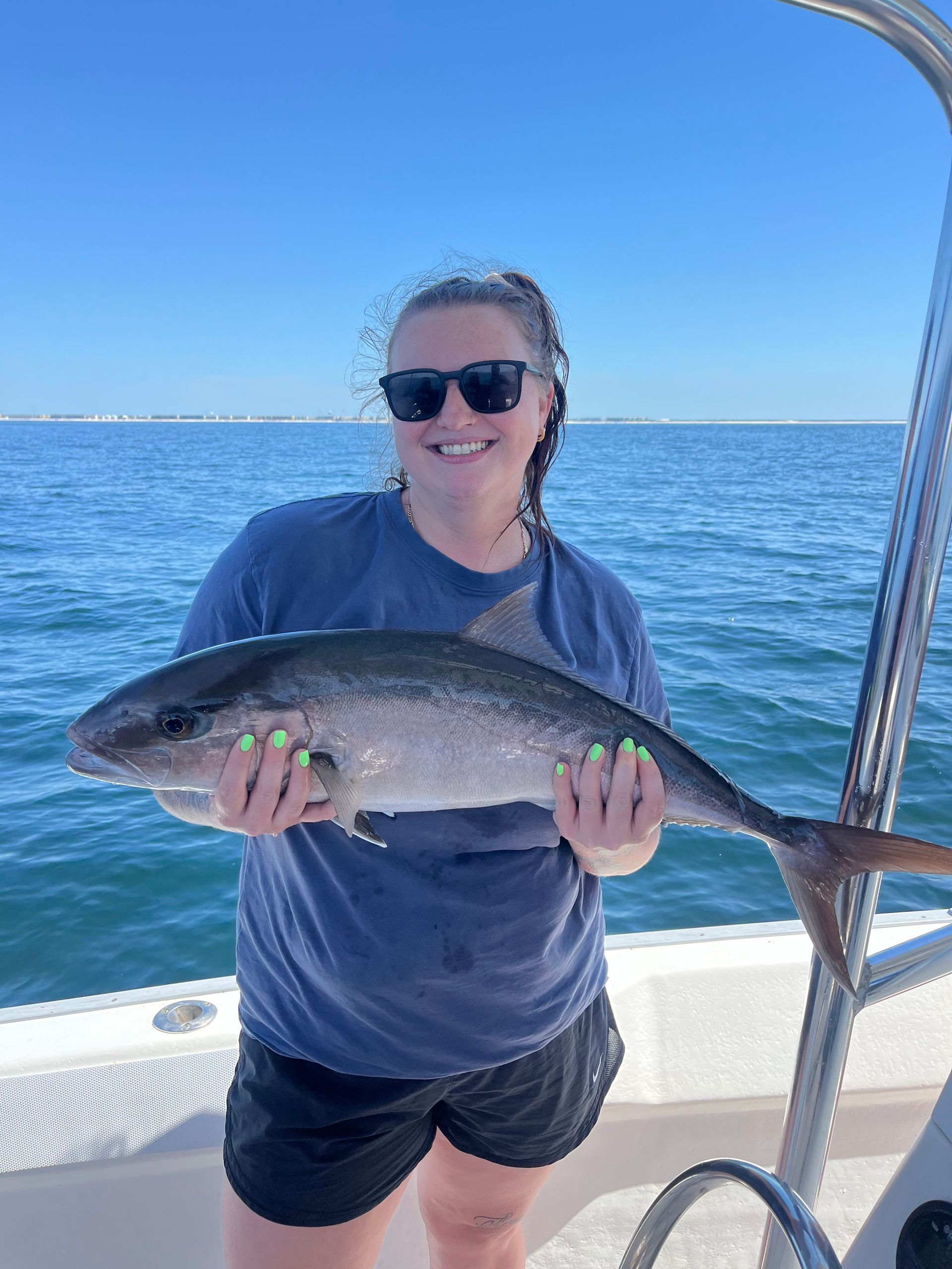 Person on a boat holding a large fish with the ocean in the background.