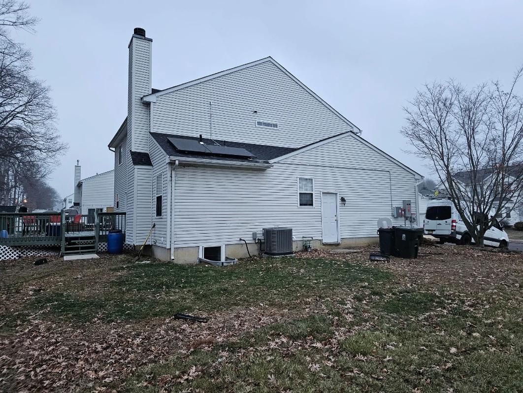 White house with weathered siding; chimney and deck visible. 
