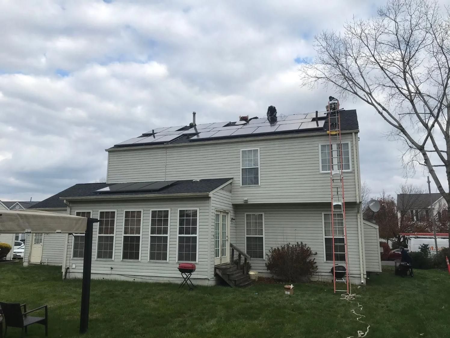 House with solar panel installation on the roof. Workers on roof. 