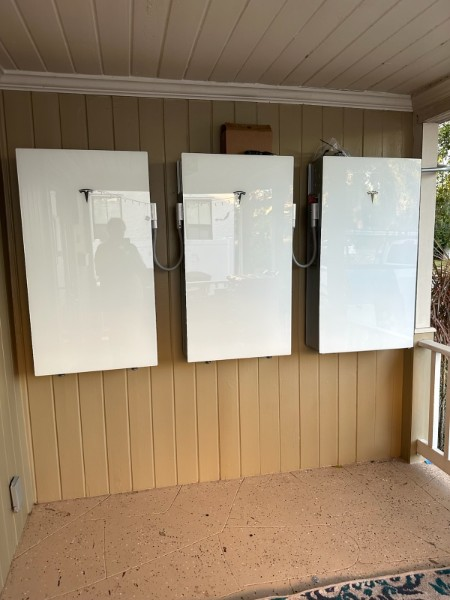 Narrow, gray-walled utility space with electrical equipment mounted on the rear wall.