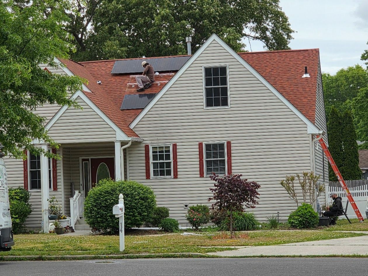 Suburban house with red roof, white siding, and a ladder leaning against the right side.