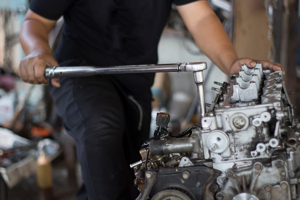 A Man Is Working on A Car Engine with A Wrench — Andy's A1 Auto Care in Barrack Heights, NSW