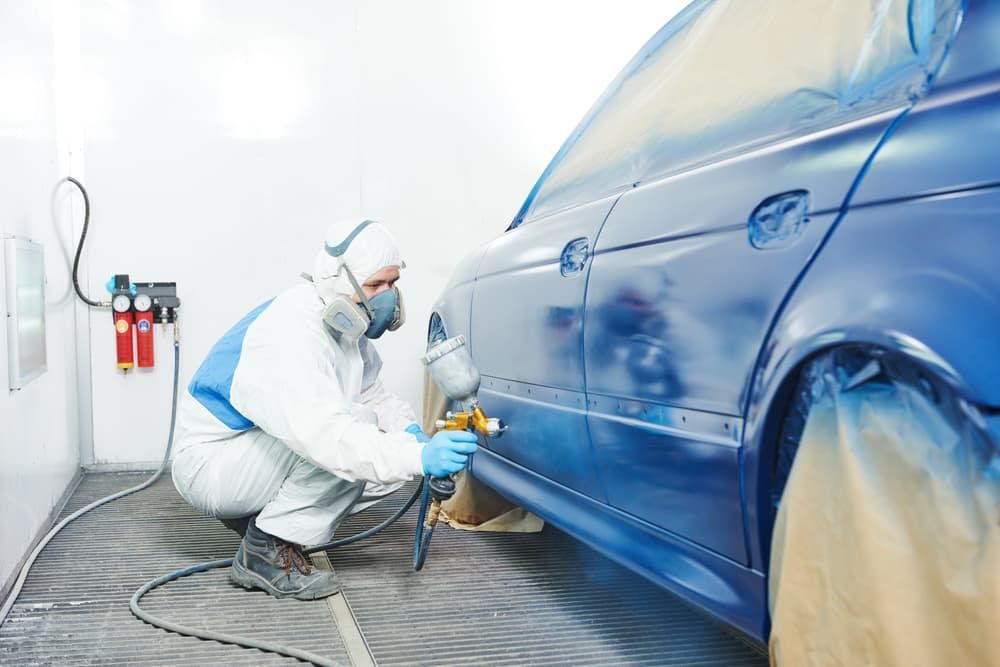 A Man Is Painting a Blue Car in A Paint Booth — Andy's A1 Auto Care in Barrack Heights, NSW