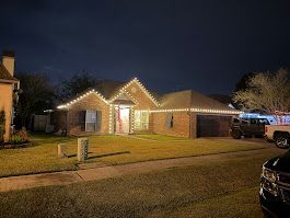 A house lit with Christmas lights at night. A car is parked in the driveway.