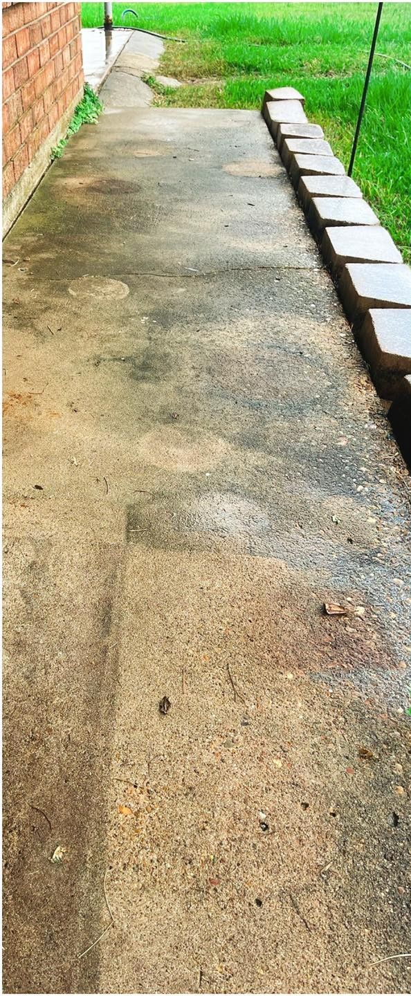 Concrete walkway next to a brick wall and grassy area with a low retaining wall.