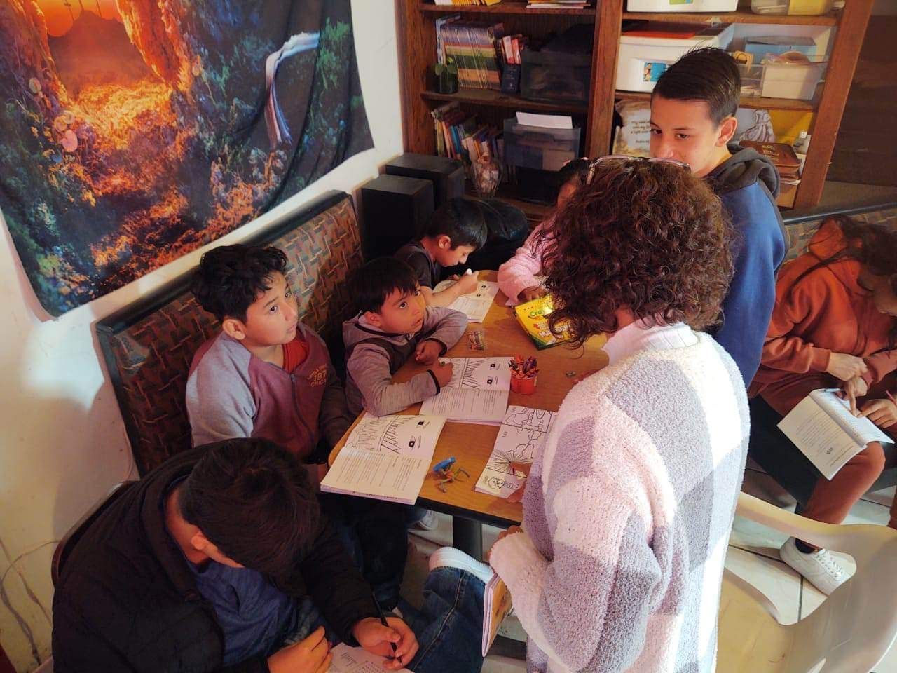 A group of children are sitting around a table with papers on it
