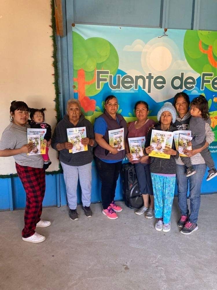 A group of people standing in front of a sign that says fuente de fe