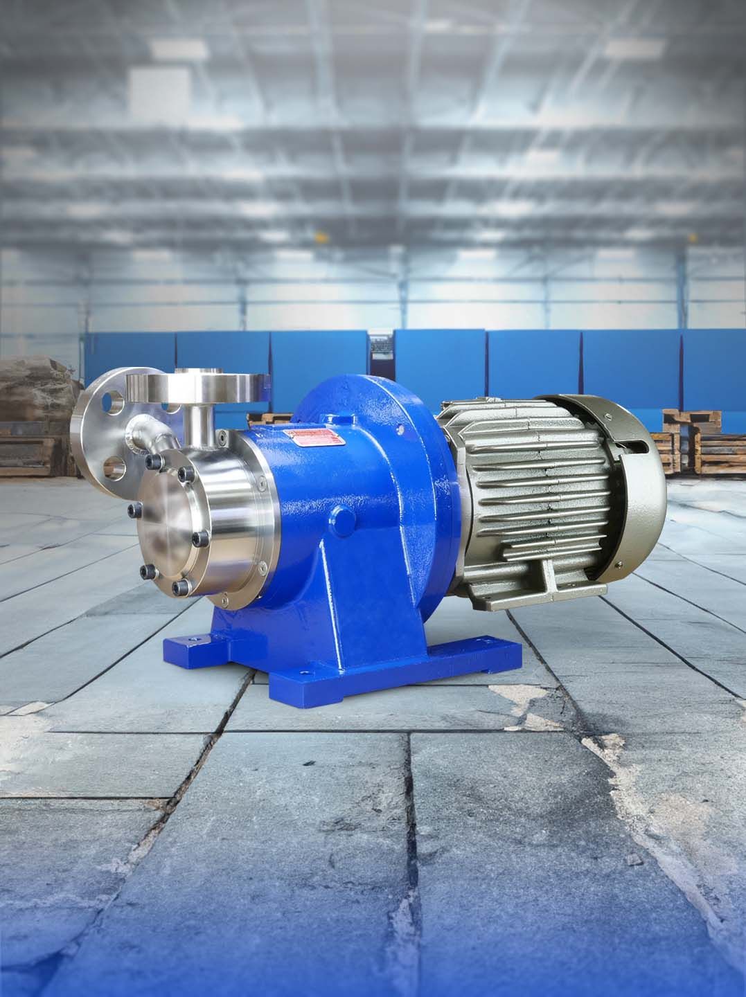 Blue industrial pump on a concrete floor, with a metal motor, against a blurred factory backdrop.